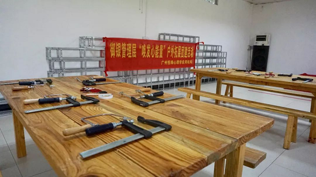 　測試不是目的，在香草拓展基地的冠軍營地，培訓機構還特別請來了黃大仙為大家解讀迷津，讓參訓的管理人員重新認識心底的自己，同時理解溝通中可能出現的障礙，與此同時，還借助測試引導管理人員轉換角度、換位思考，借此提高溝通的效能。不僅如此，黃大仙還在介紹過程中為參訓人員提供了一些提升管理的溝通小秘籍。     經歷匠人精神     　　沒有真正的經歷，又談何真正的理解與認識。管理人員來自不同的部門、不同的領域，為了加深理解與認識，培訓進入了第二個環節——體驗木藝工作坊。每人一個F夾、一把手持鋸，一到兩塊木板、幾幅看似有些朦朧的造型圖、鉛筆、剪刀、砂紙，還有作品任務書，工作坊正式啟動。